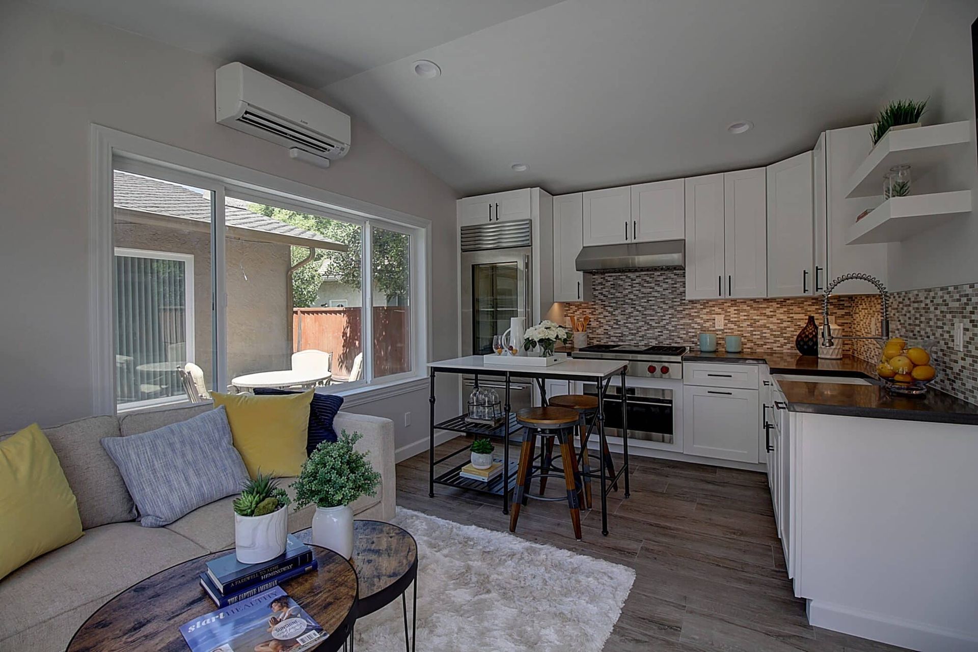 A living room with a couch , table , chairs and a kitchen.