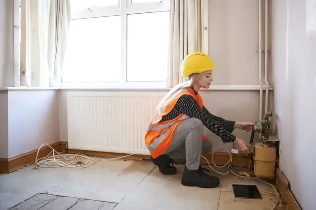 A woman in a hard hat is kneeling down in a room.