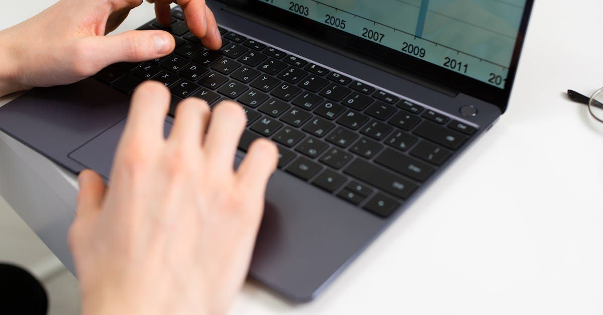 A person is typing on a laptop computer with a graph on the screen.