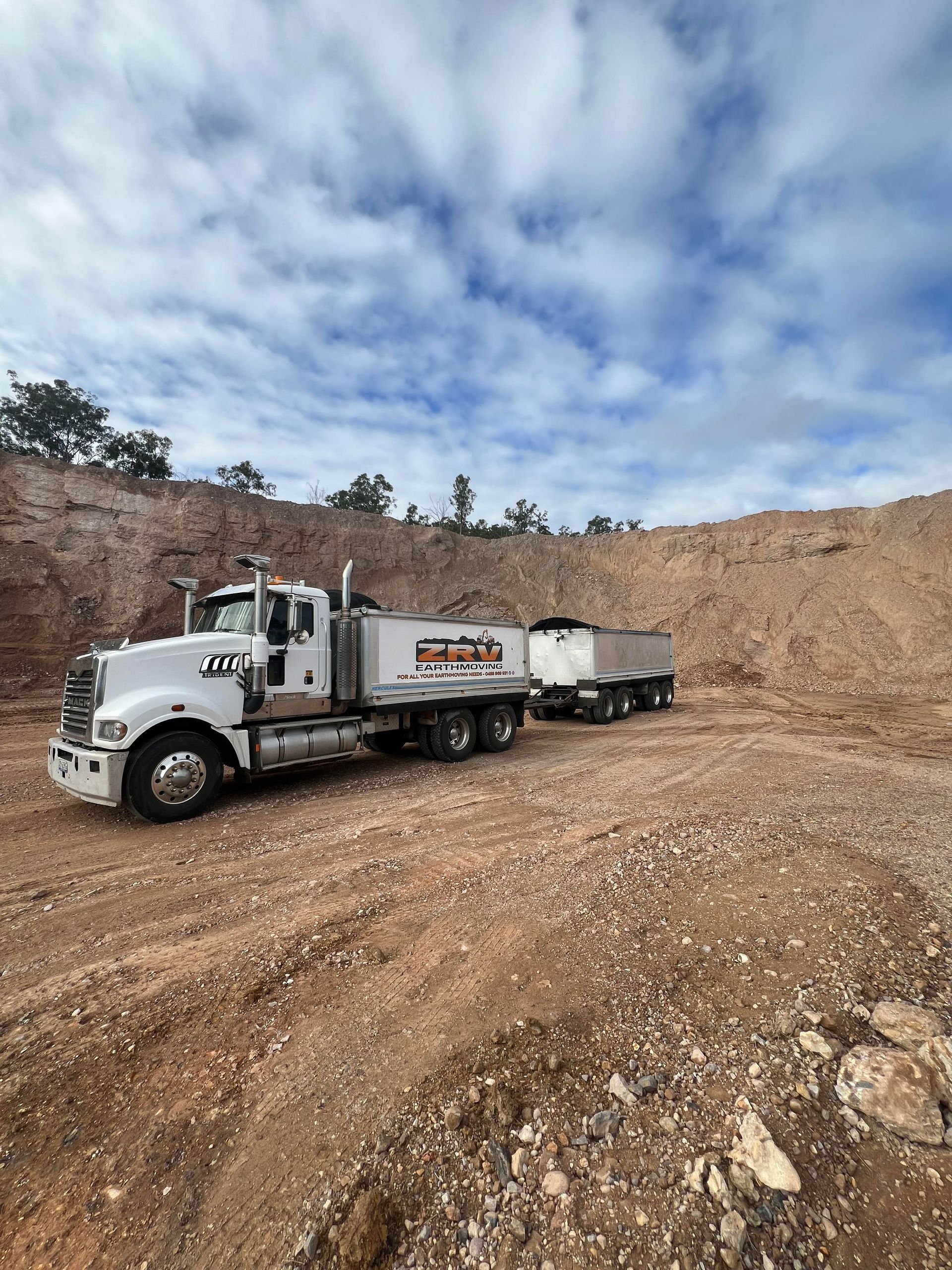 A truck is carrying a small excavator on a trailer.