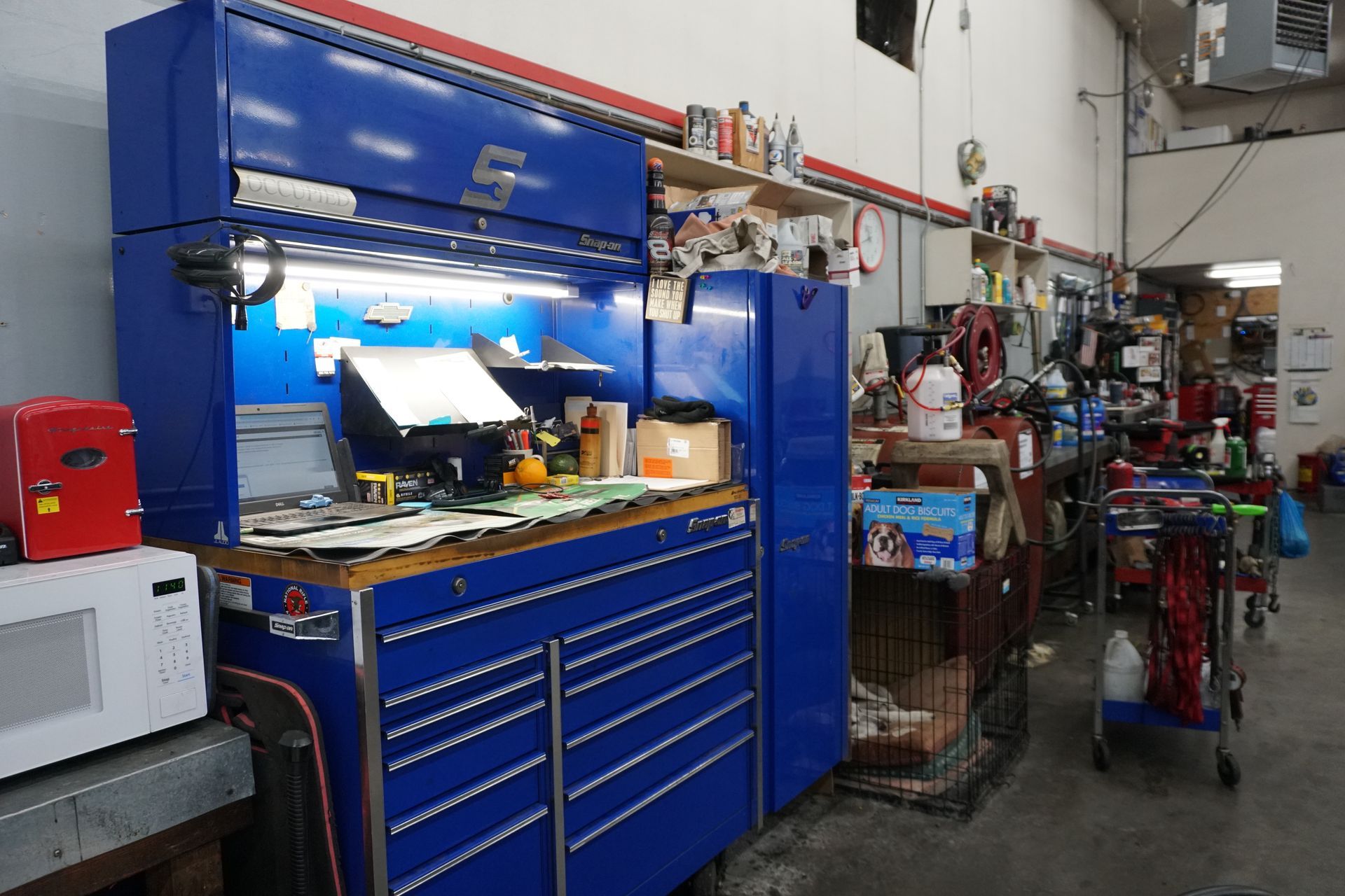 Blue tool chest in a workshop setting with various tools and supplies visible.