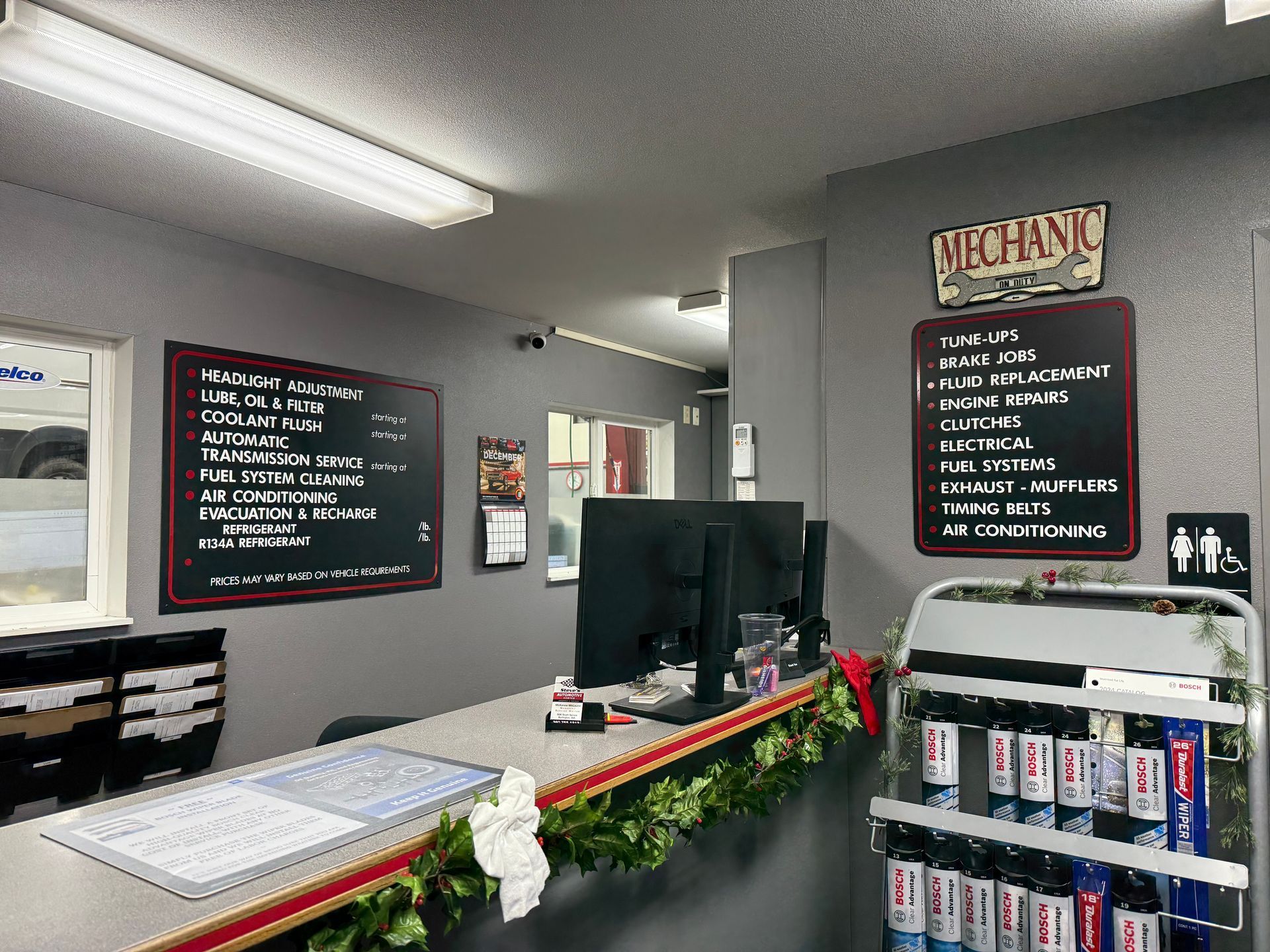 Interior of a mechanic shop with a counter, computer, and service menu boards.