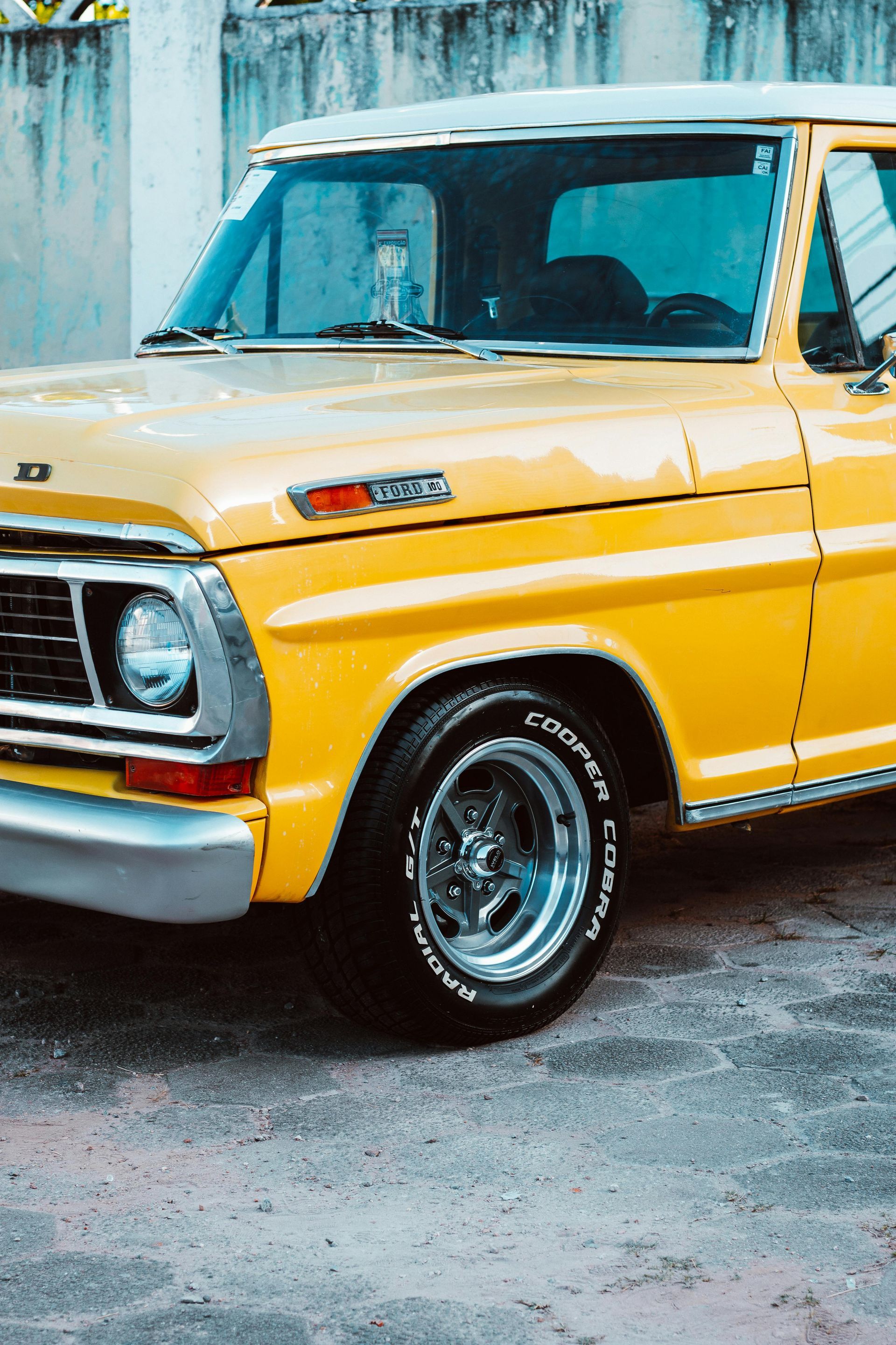 Yellow vintage Ford truck, parked outdoors.