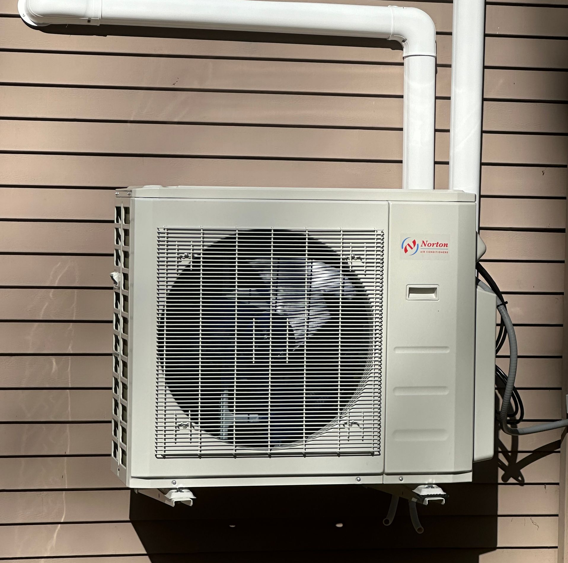 White radiator near a window and gray sofa in a room with a curtain.