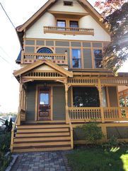 Two-story house with wooden trim, front porch, steps, and siding in various colors.