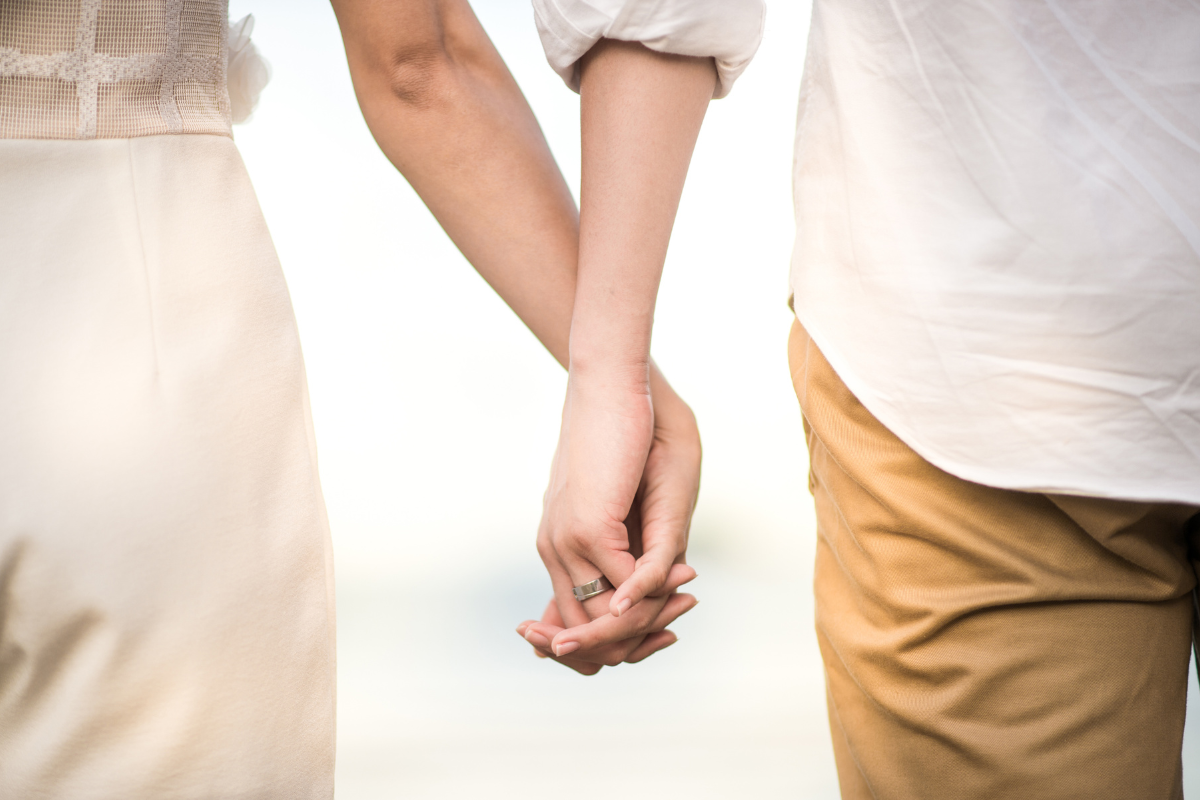 a man and a woman are holding hands on the beach .