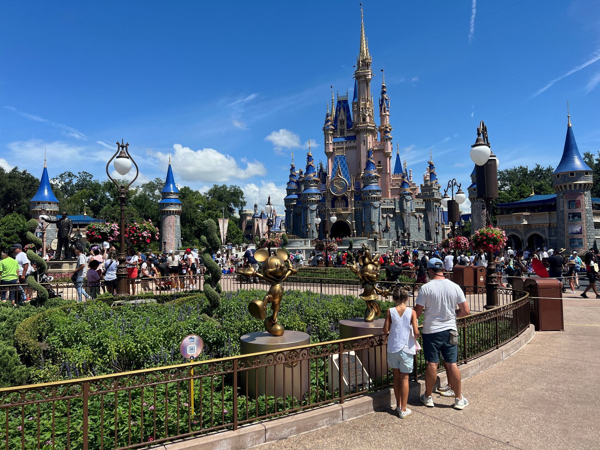 a couple of people standing in front of a castle at a theme park .