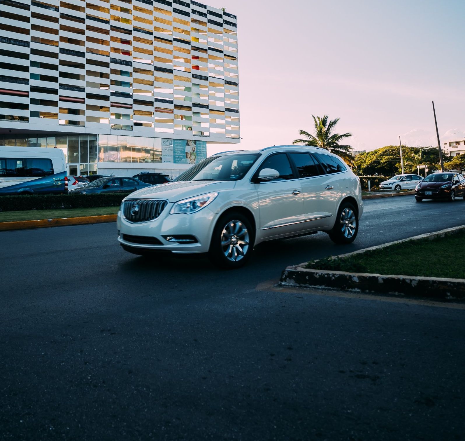 a white suv is driving down a street in front of a building