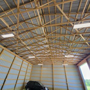 A car is parked inside of a garage with a wooden roof.