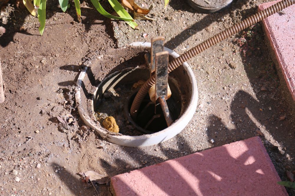 A Man Is Standing In The Dirt Next To A Pipe — Gold Coast Leak Detection In Burleigh Heads, QLD