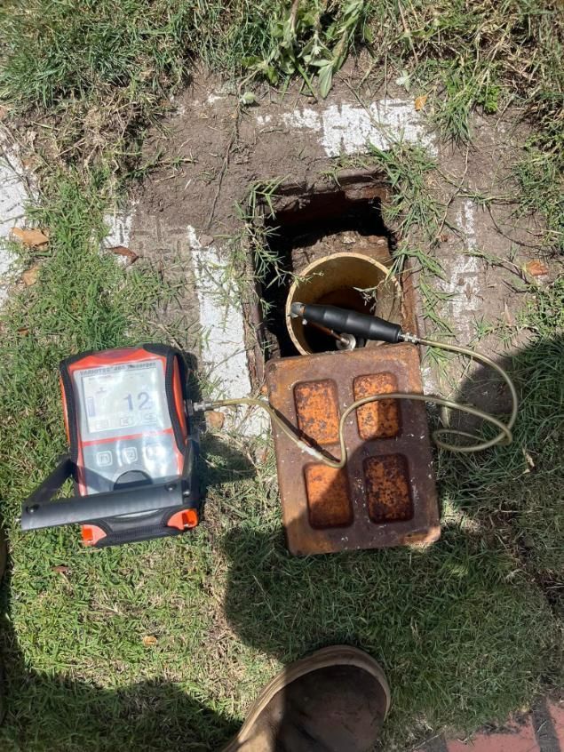 A Manhole Cover is Being Opened and a Device is Sitting Next to It — Gold Coast Leak Detection in Mudgeeraba, QLD