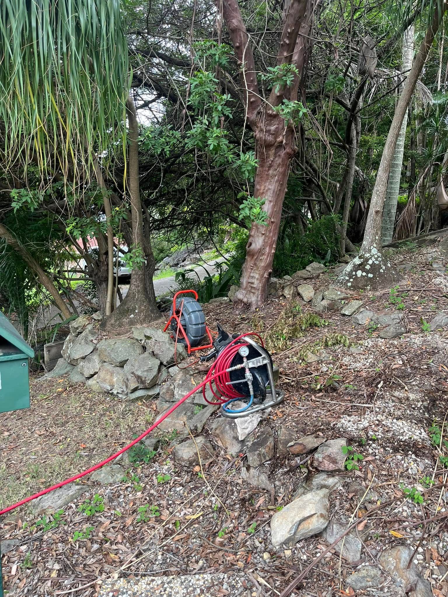 Red Hose Reel on a Rocky Hillside Next to Trees and Greenery — Gold Coast Leak Detection in Tallai, QLD