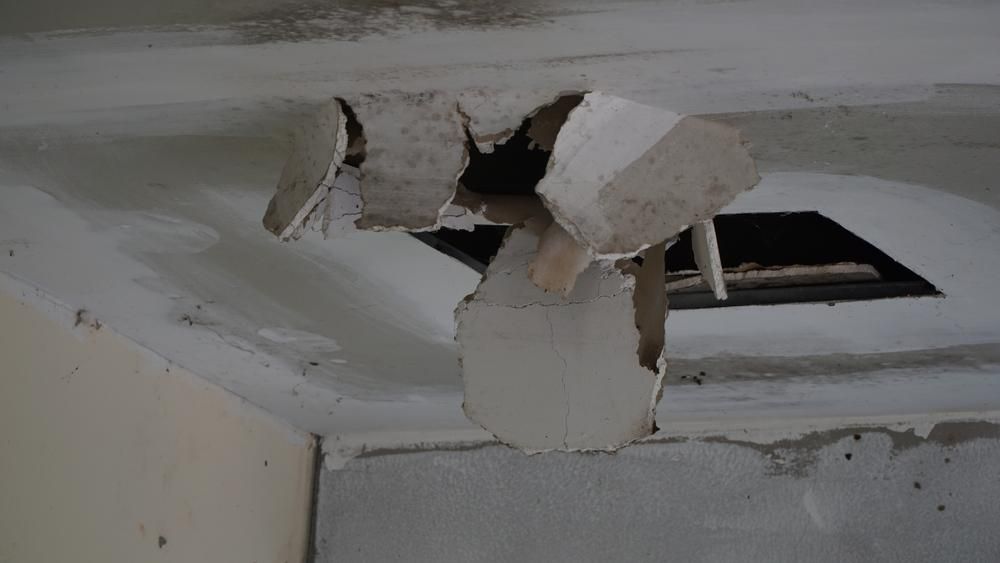 A Ceiling With a Hole in It and a Piece of Plaster Hanging From It — Gold Coast Leak Detection in Mudgeeraba, QLD