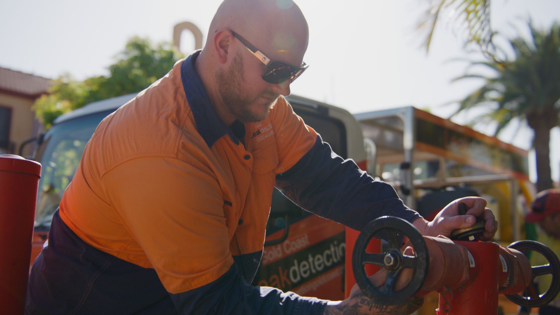 A Man in an Orange Shirt is Working on a Fire Hydrant — Gold Coast Leak Detection in Mudgeeraba, QLD