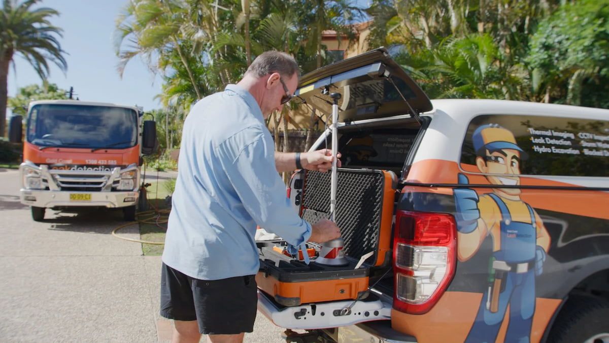 A Man is Cleaning a Manhole Cover With a Bucket — Gold Coast Leak Detection in Mudgeeraba, QLD