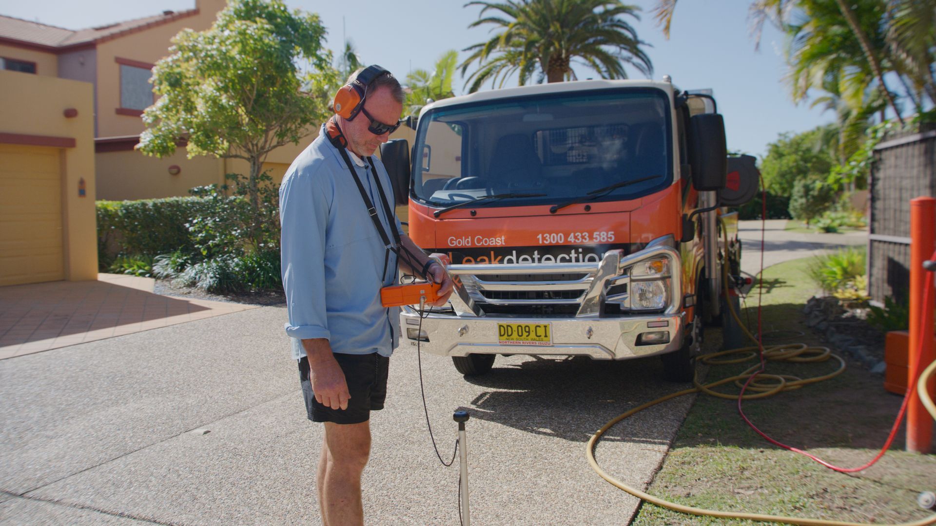 A Sprinkler Is Spraying Water In Front Of A Pile Of Wood Chips — Gold Coast Leak Detection In Robina, QLD