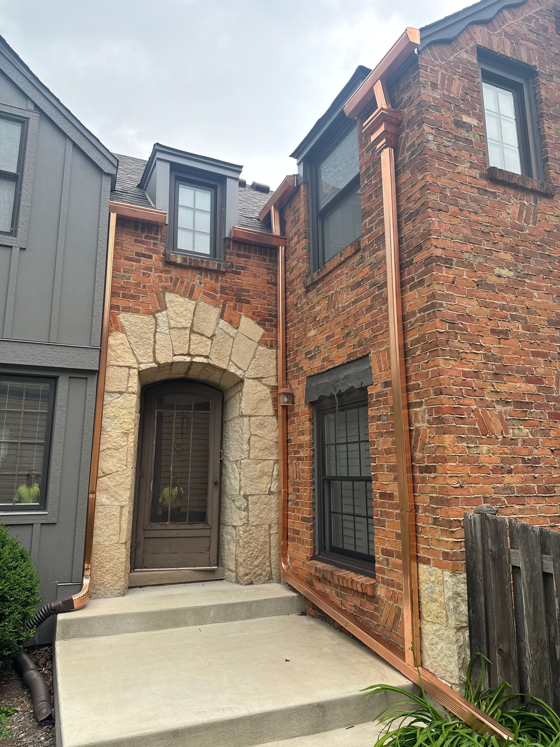A brick house with a copper gutter on the side of it