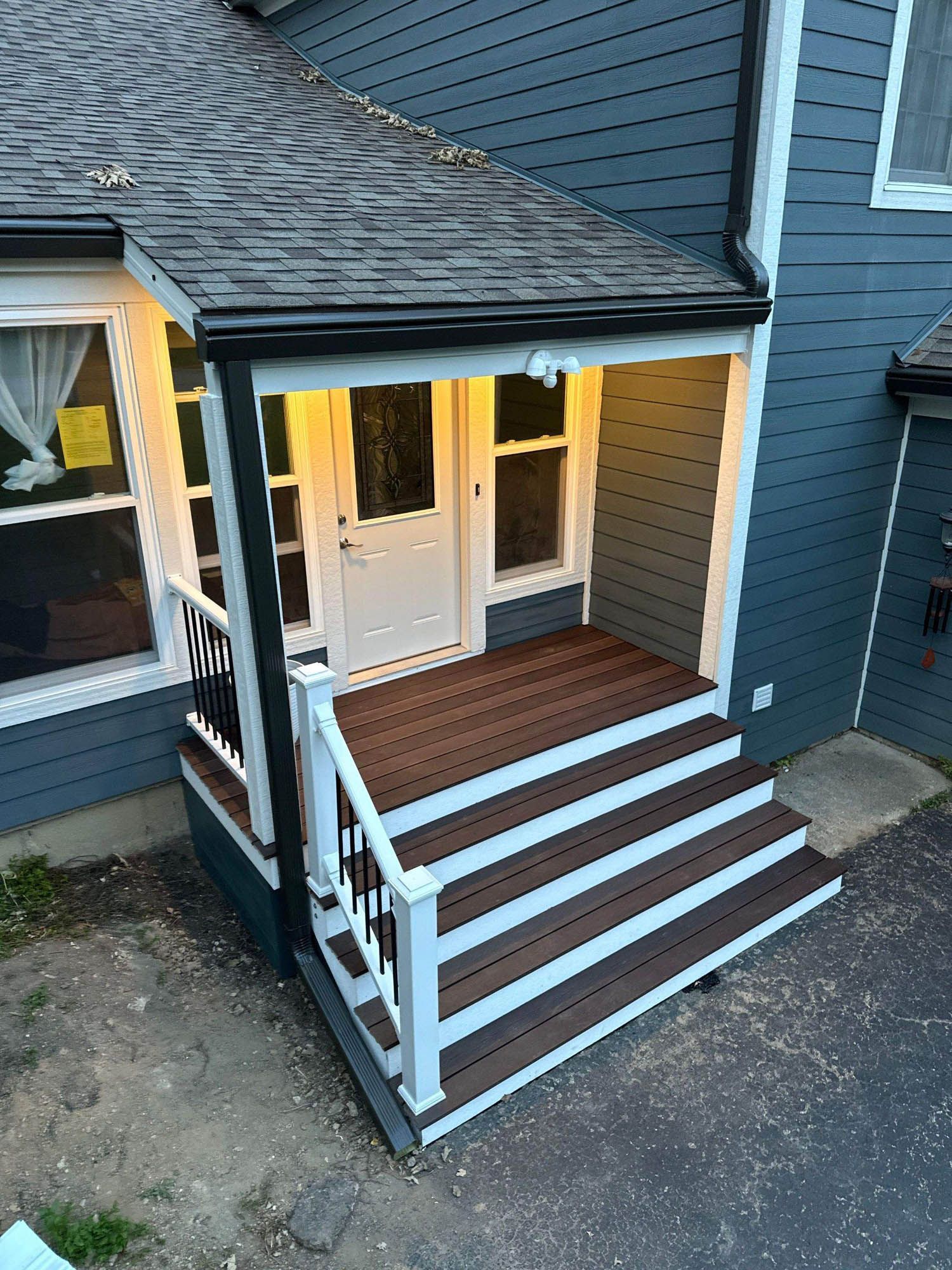 A porch with stairs leading up to the front door of a house.