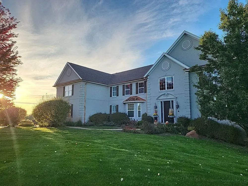 A large white house with a lush green lawn in front of it.