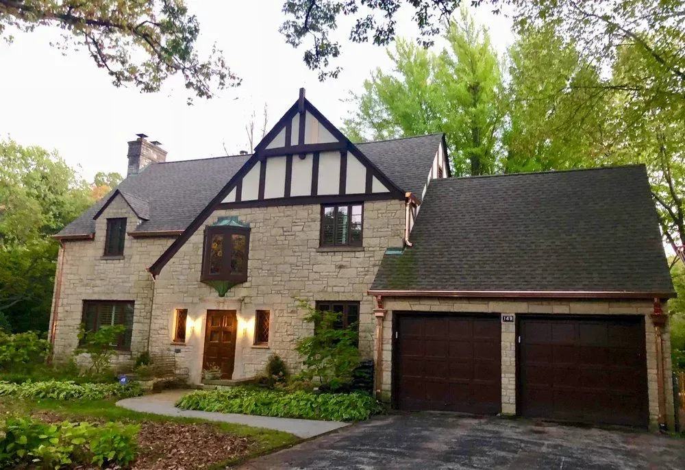A large brick house with two garage doors and a copper gutter