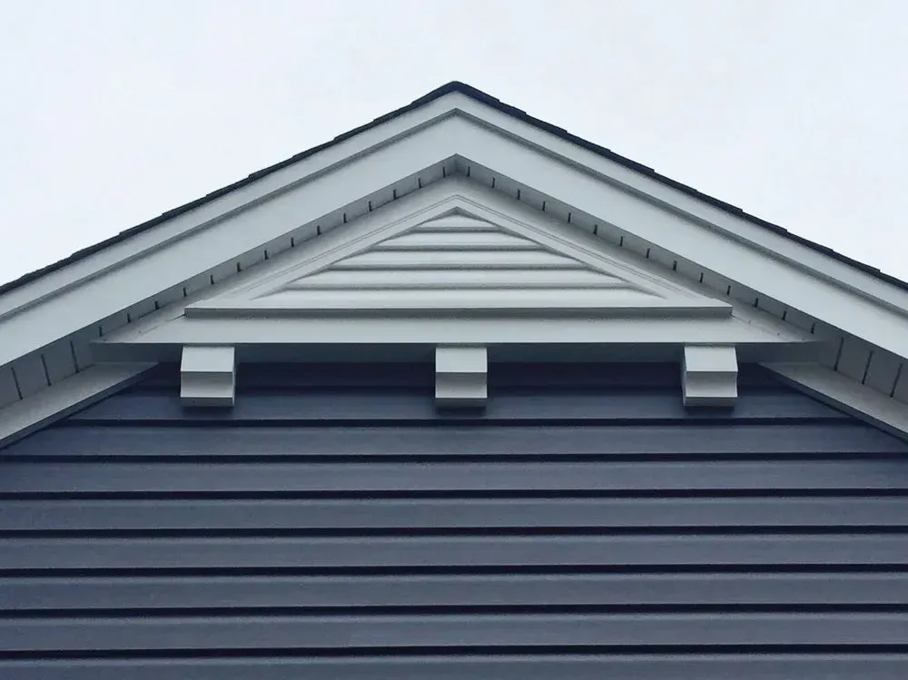 A blue house with a white trim on the roof