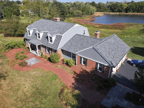 An aerial view of a large house with a lake in the background.