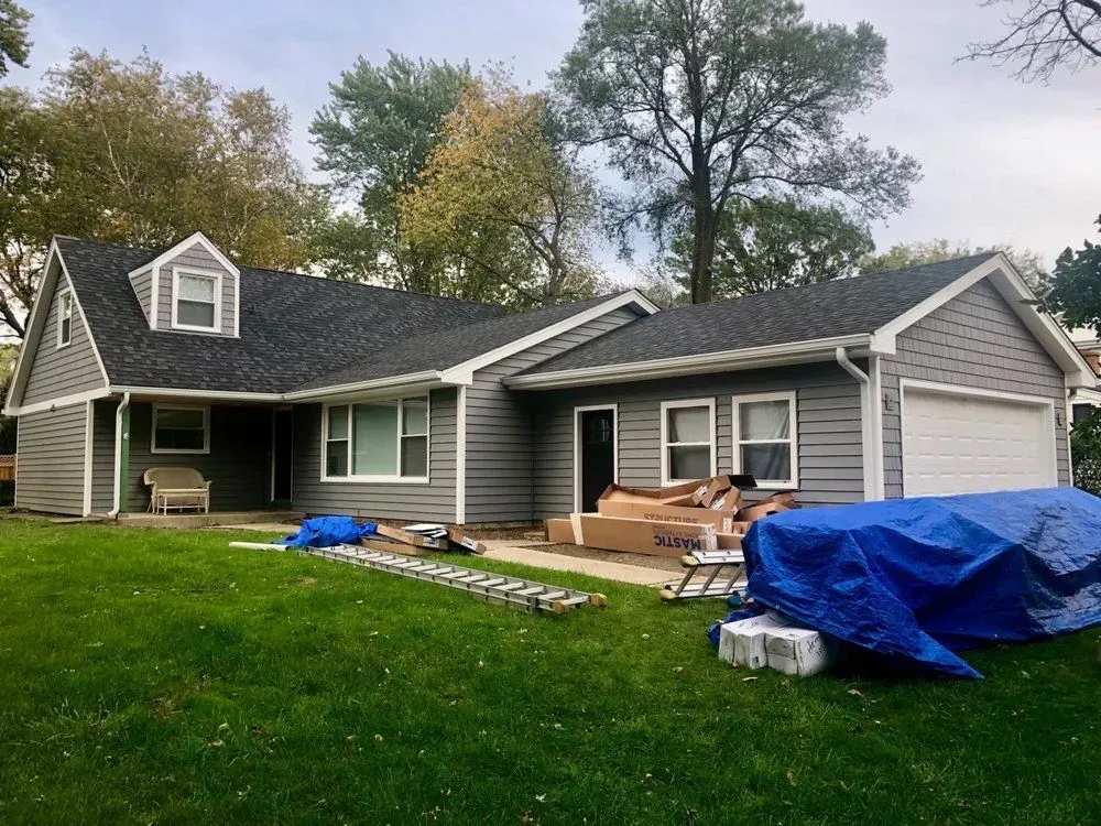 A gray house with a black roof is being remodeled.