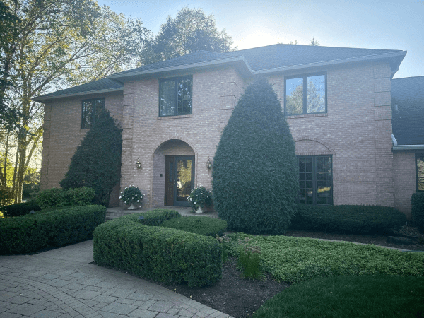 A large brick house with a lot of windows and bushes in front of it.