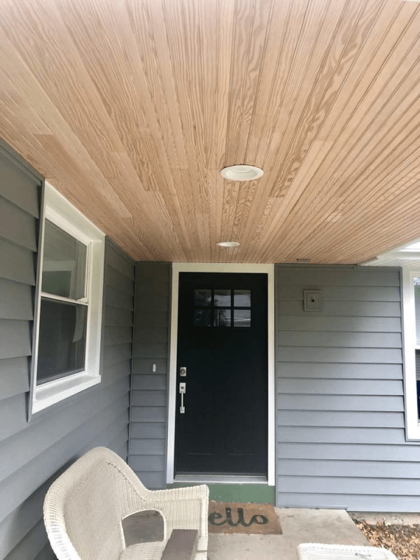The front porch of a house with a wooden ceiling