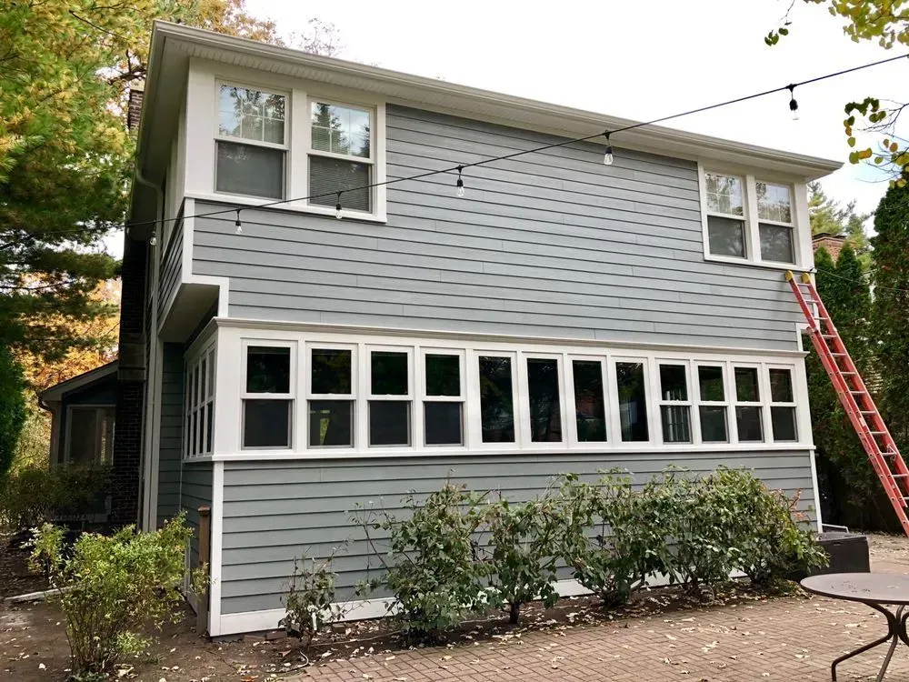 A house with a lot of windows and a ladder on the side of it.