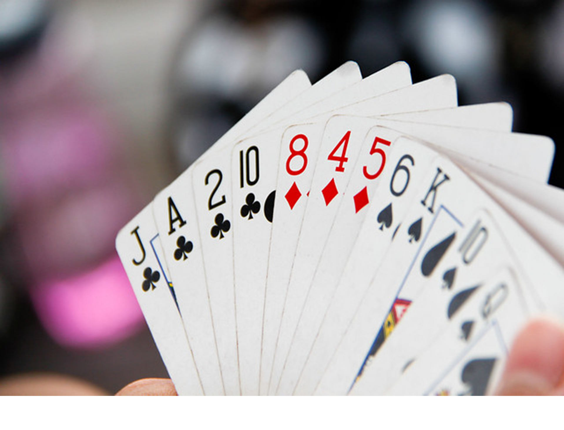 A person is holding a fan of playing cards including a royal flush