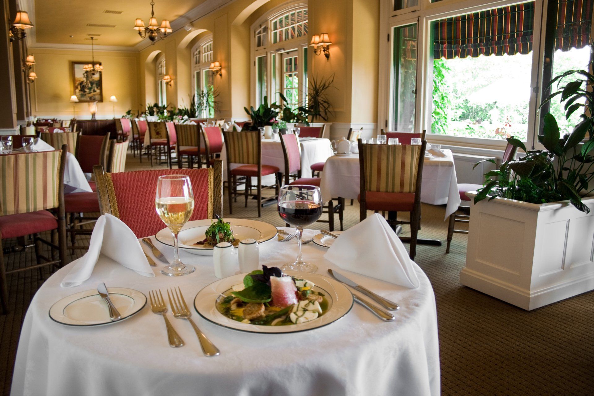 Romantic dinner with couple, red roses, candles, and wine on a table, soft lighting.