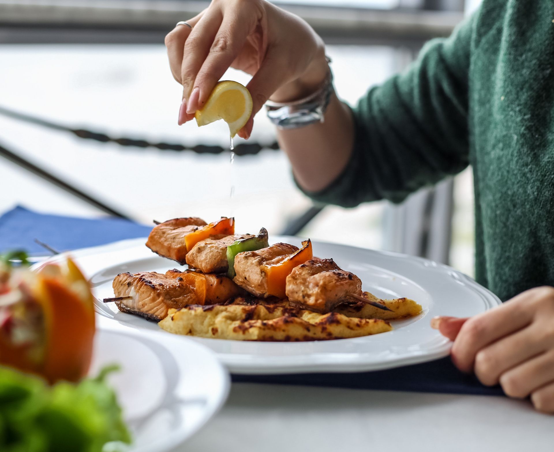 A person is squeezing lemon juice on a plate of food