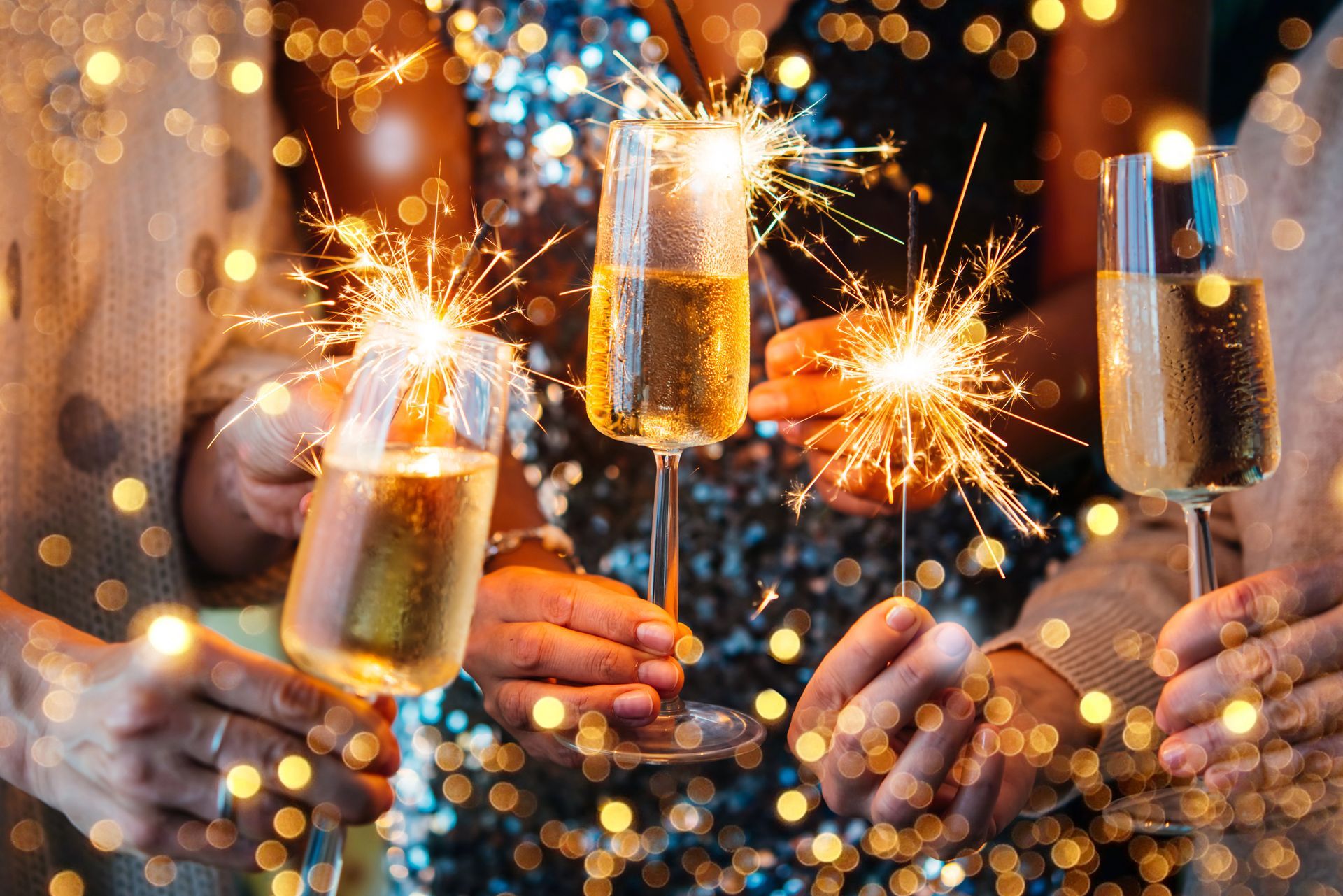 Sparkling champagne flutes with sparklers, festive celebration with bokeh lights.