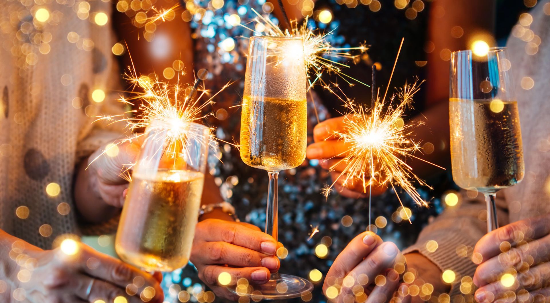 A group of people are holding sparklers and champagne glasses.