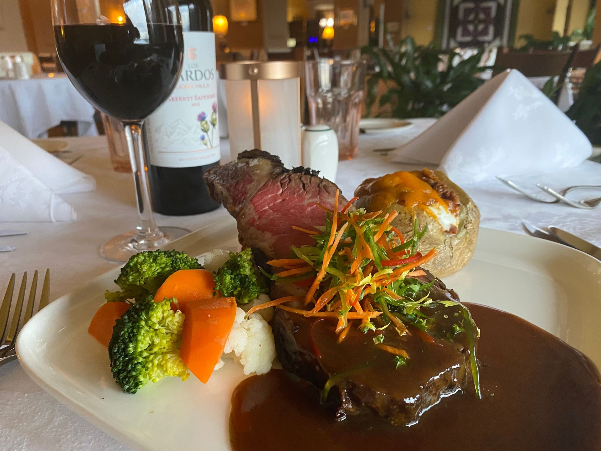 A plate of food with a bottle of wine in the background