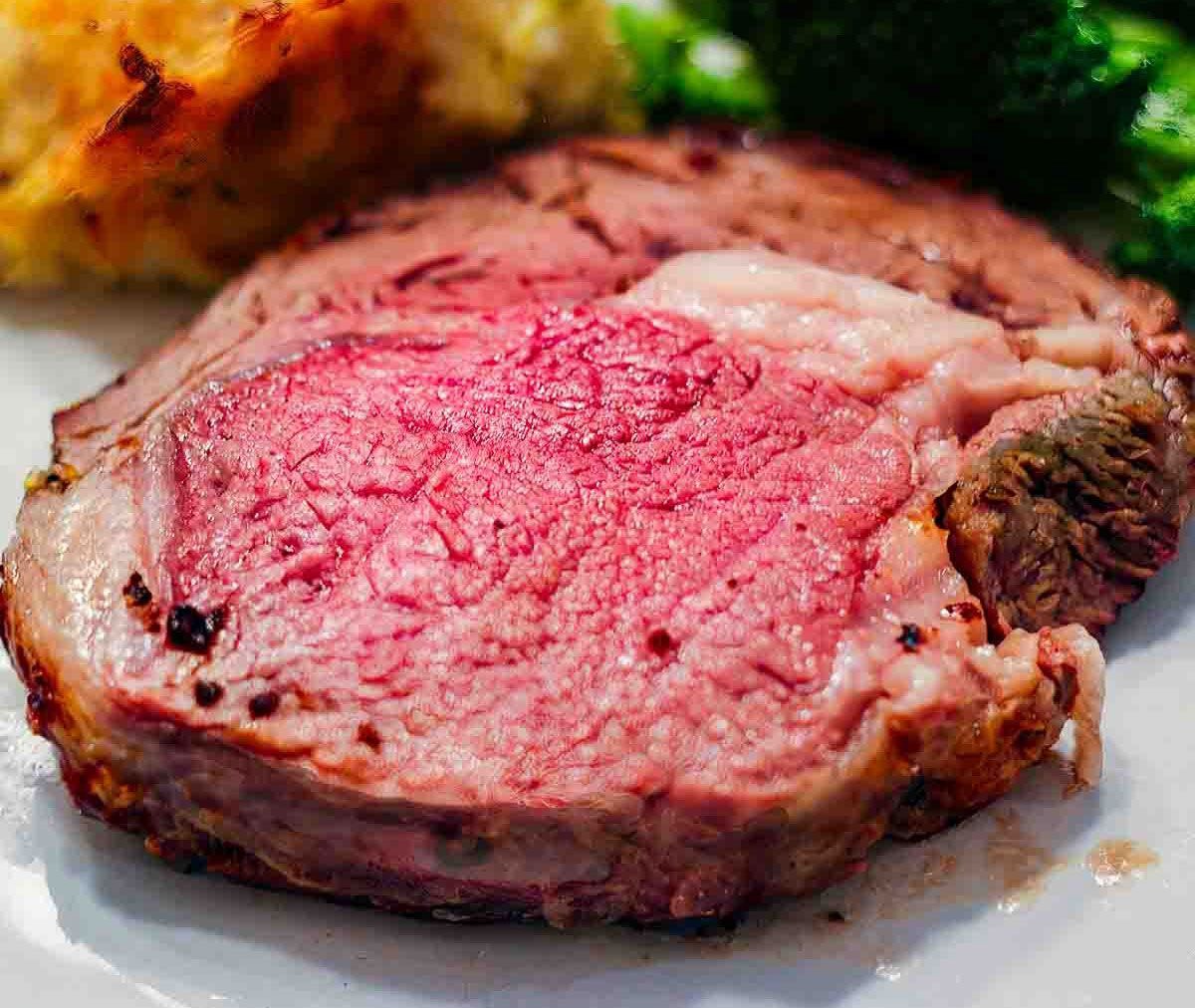 Plate of prime rib, green beans and a loaded baked potato.