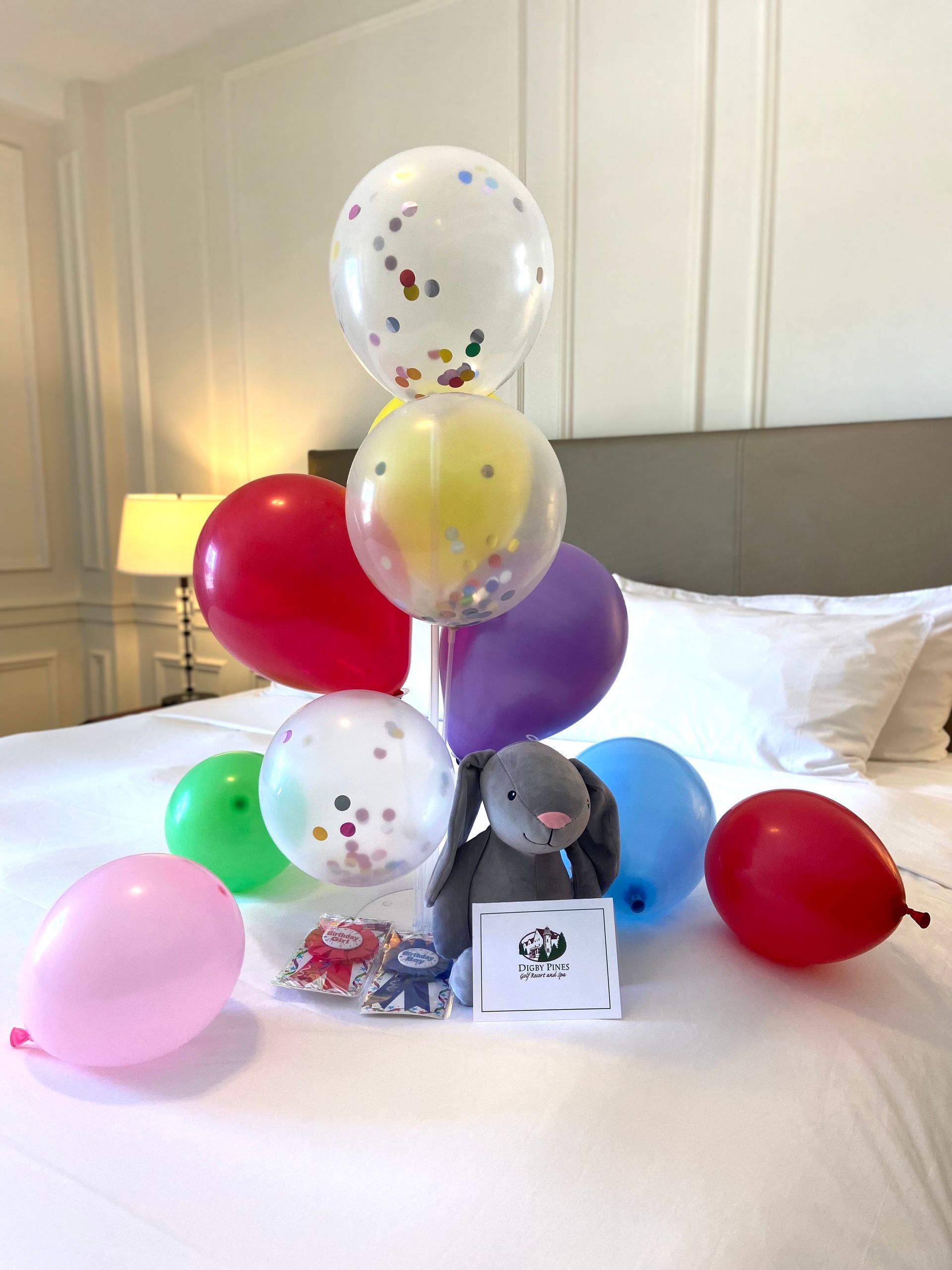 a bed with balloons and a stuffed elephant on it .