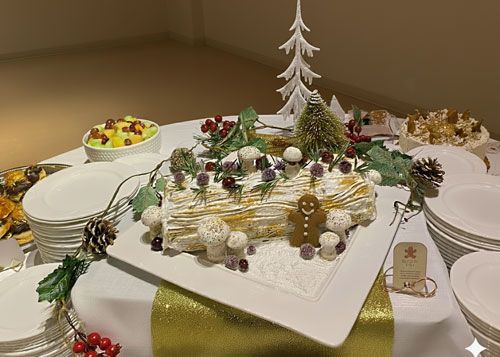 Christmas dessert table with a log cake, decorations, and plates.