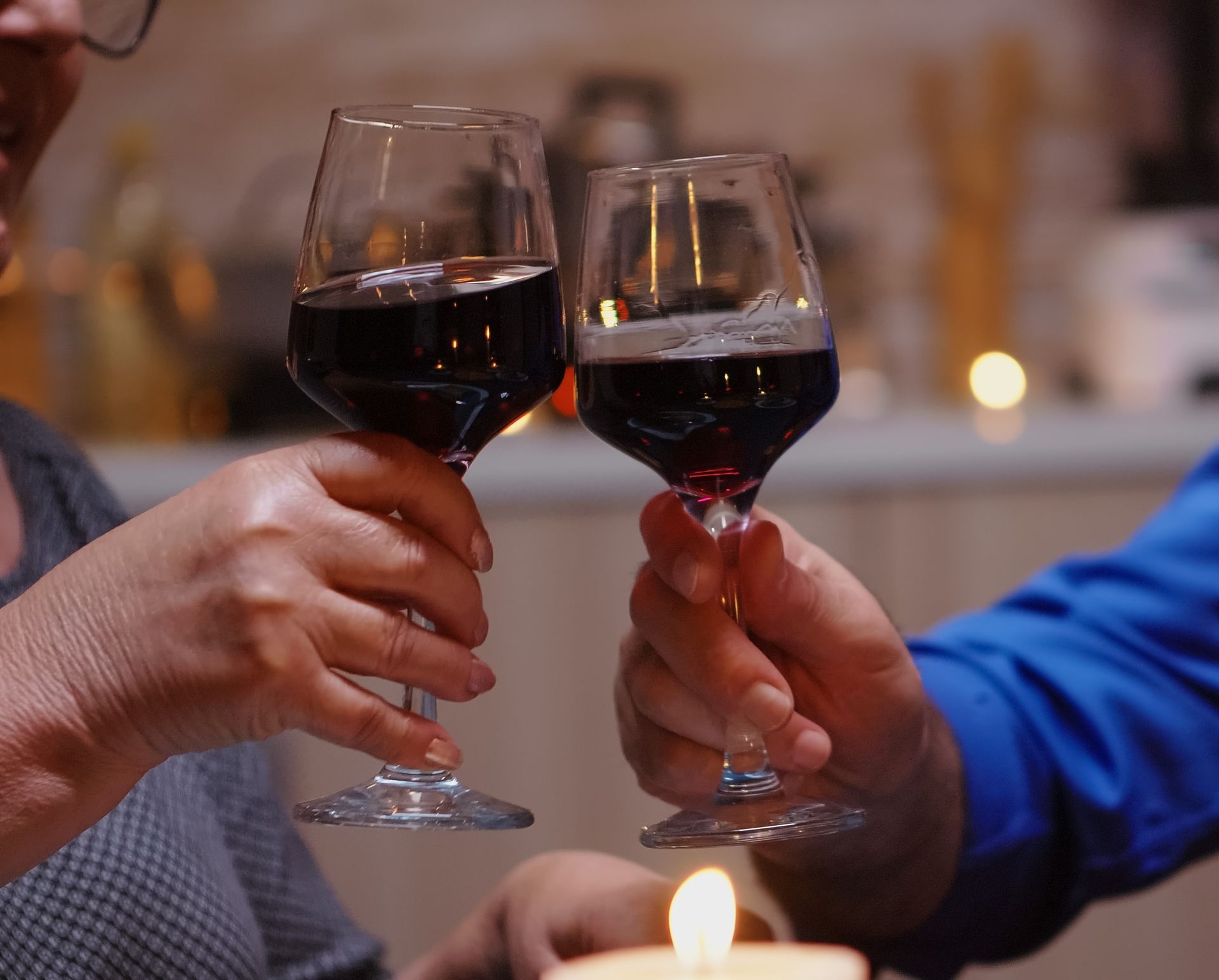 A man and a woman are toasting with wine glasses and a candle.