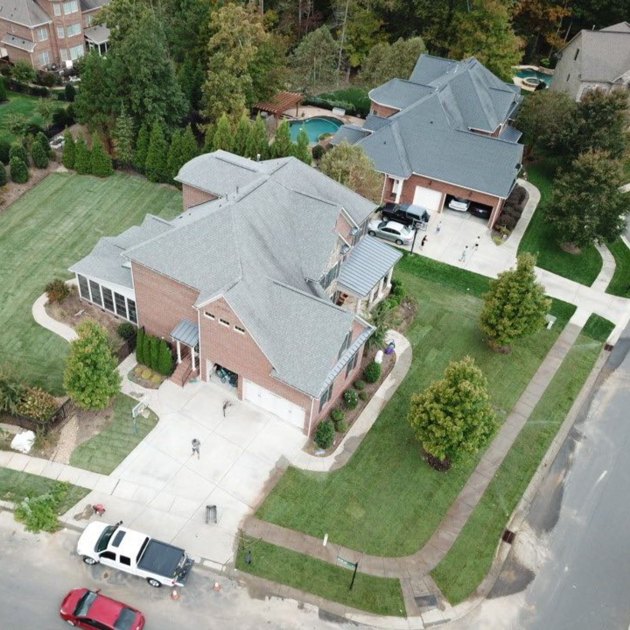 An aerial view of a large brick house with a gray roof