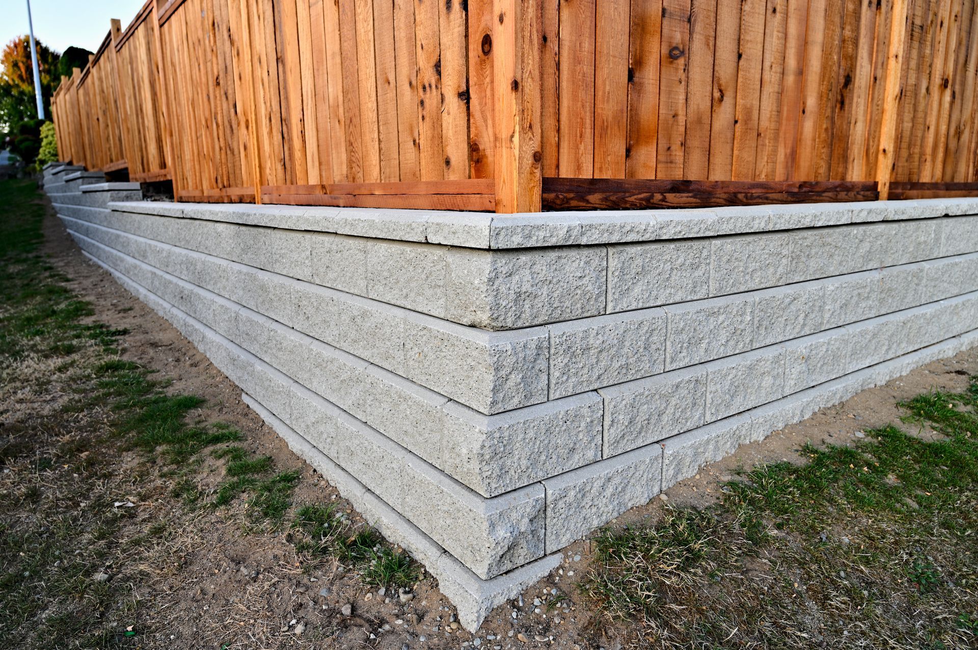 A wooden fence is behind a stone wall.