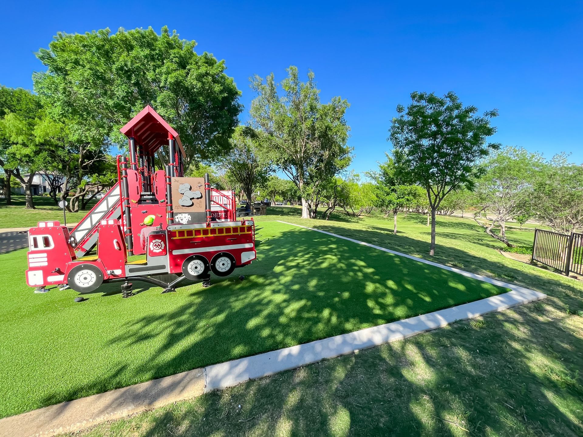 A playground in the shape of a fire truck in a park.