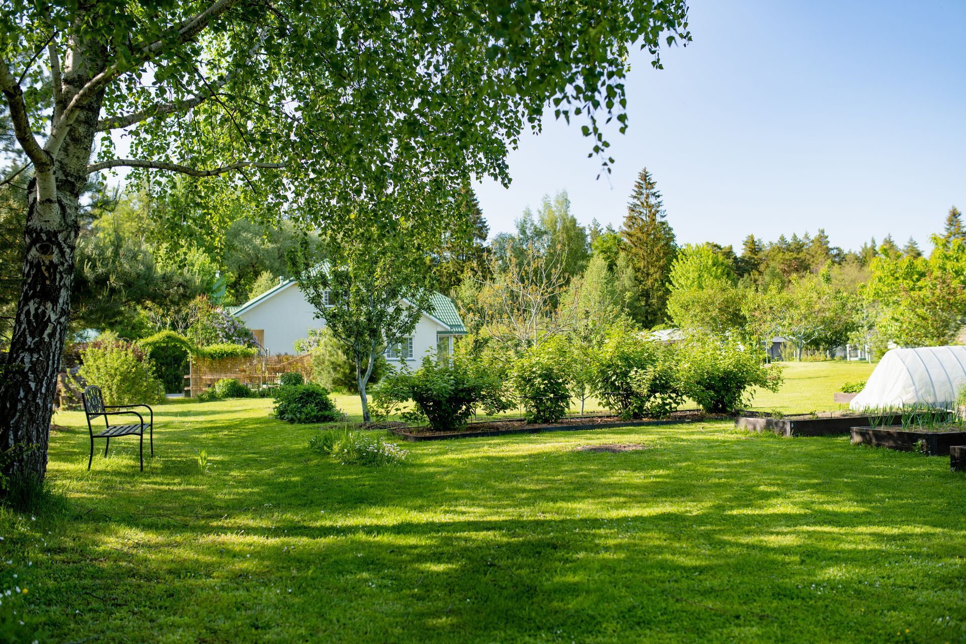 There is a greenhouse in the middle of a lush green field.