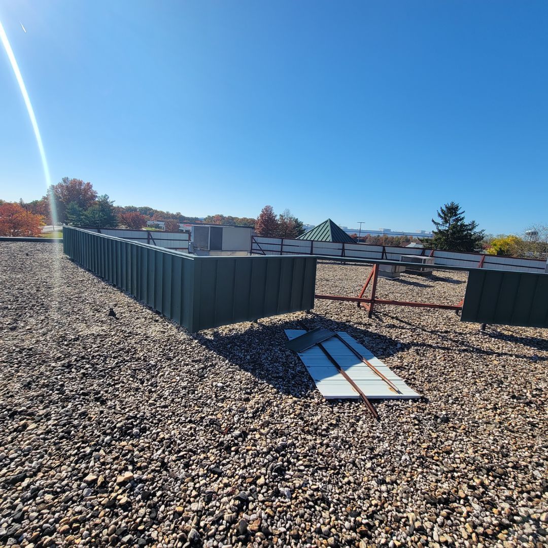 A fence is sitting on top of a gravel covered roof.