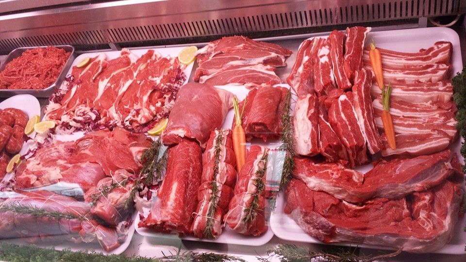 Due persone che tengono bicchieri di vino e un piatto di cibo davanti a un cartello che dice la playa
