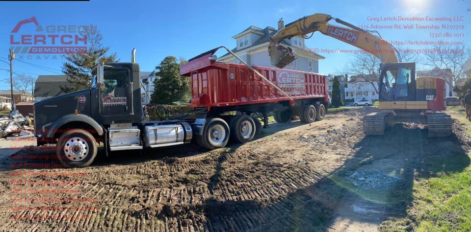 A dump truck is driving down a dirt road next to an excavator