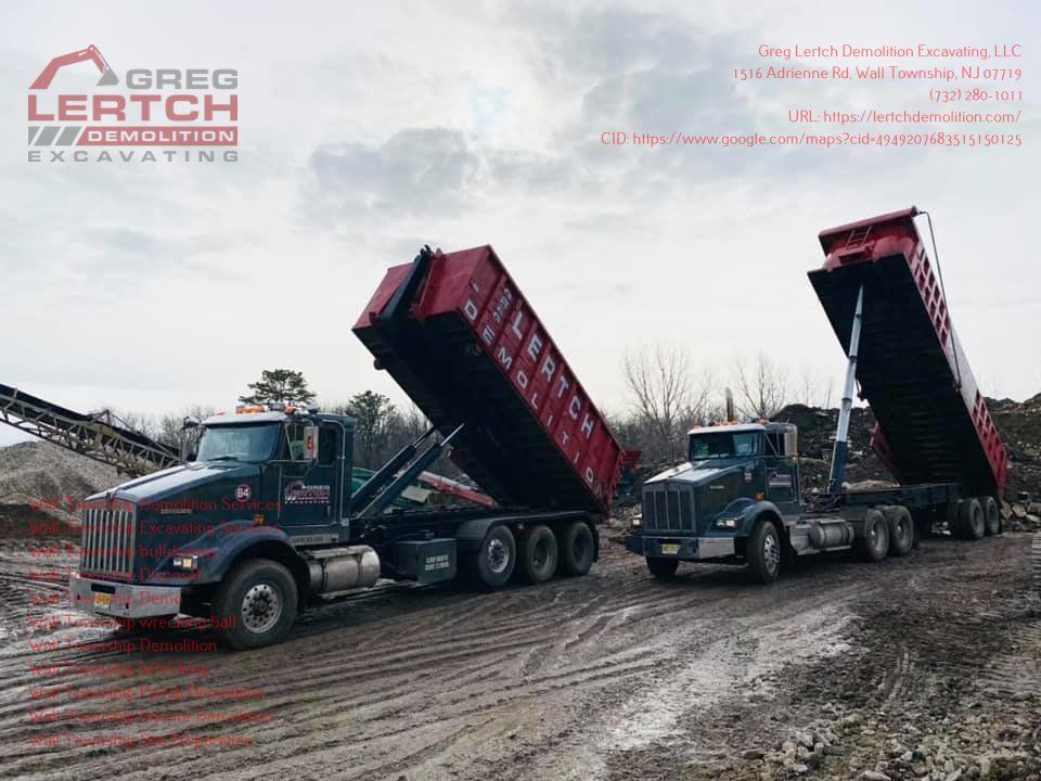 Two dump trucks are parked next to each other on a dirt road