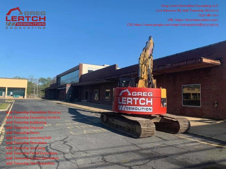 A large excavator is parked in front of a building that says greg lertch