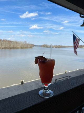 A drink in a glass on a balcony overlooking a body of water